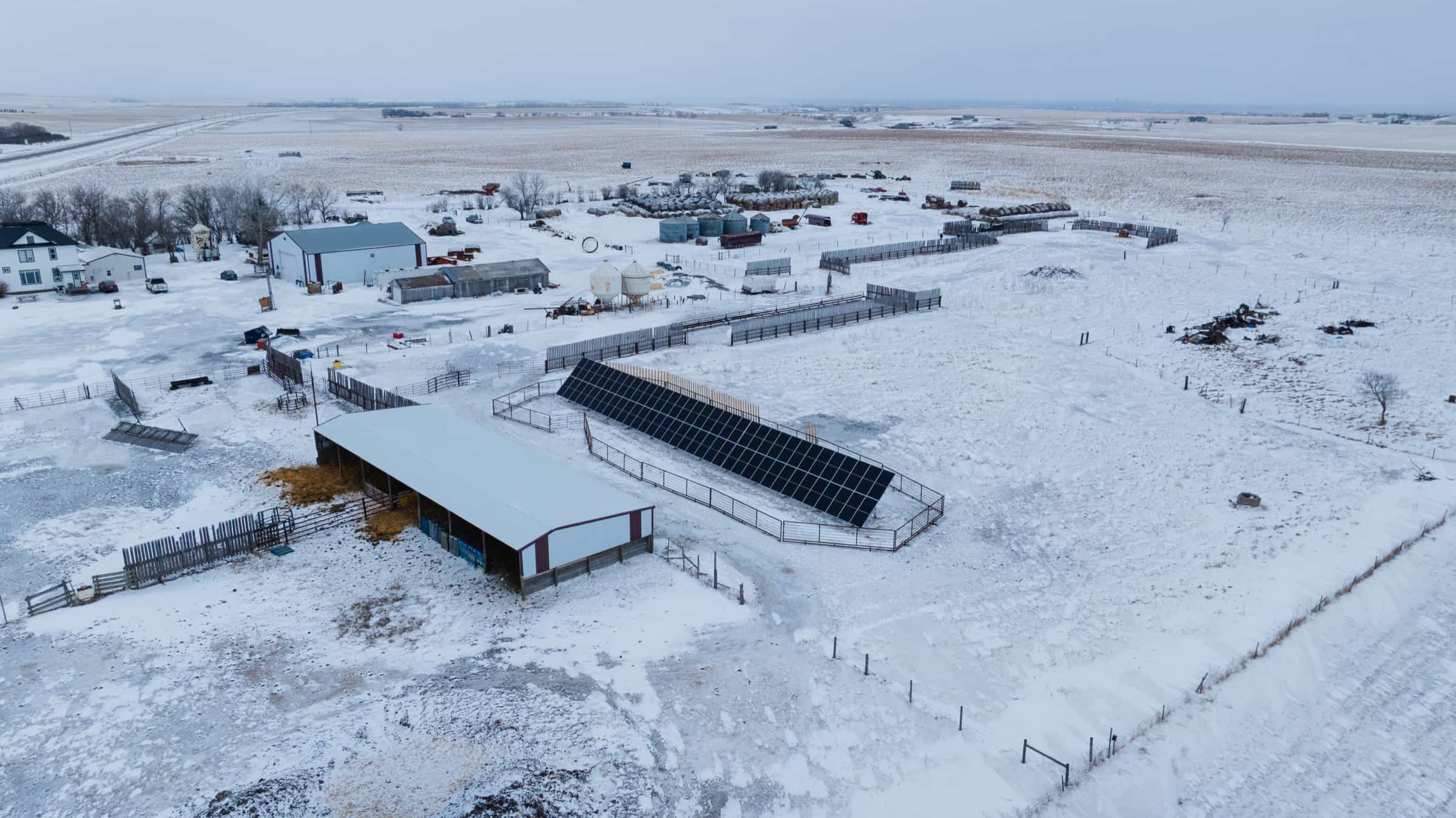 Aerial view of the Mackenzie farmyard in winter, with the ground-mount solar array running alongside a livestock shelter