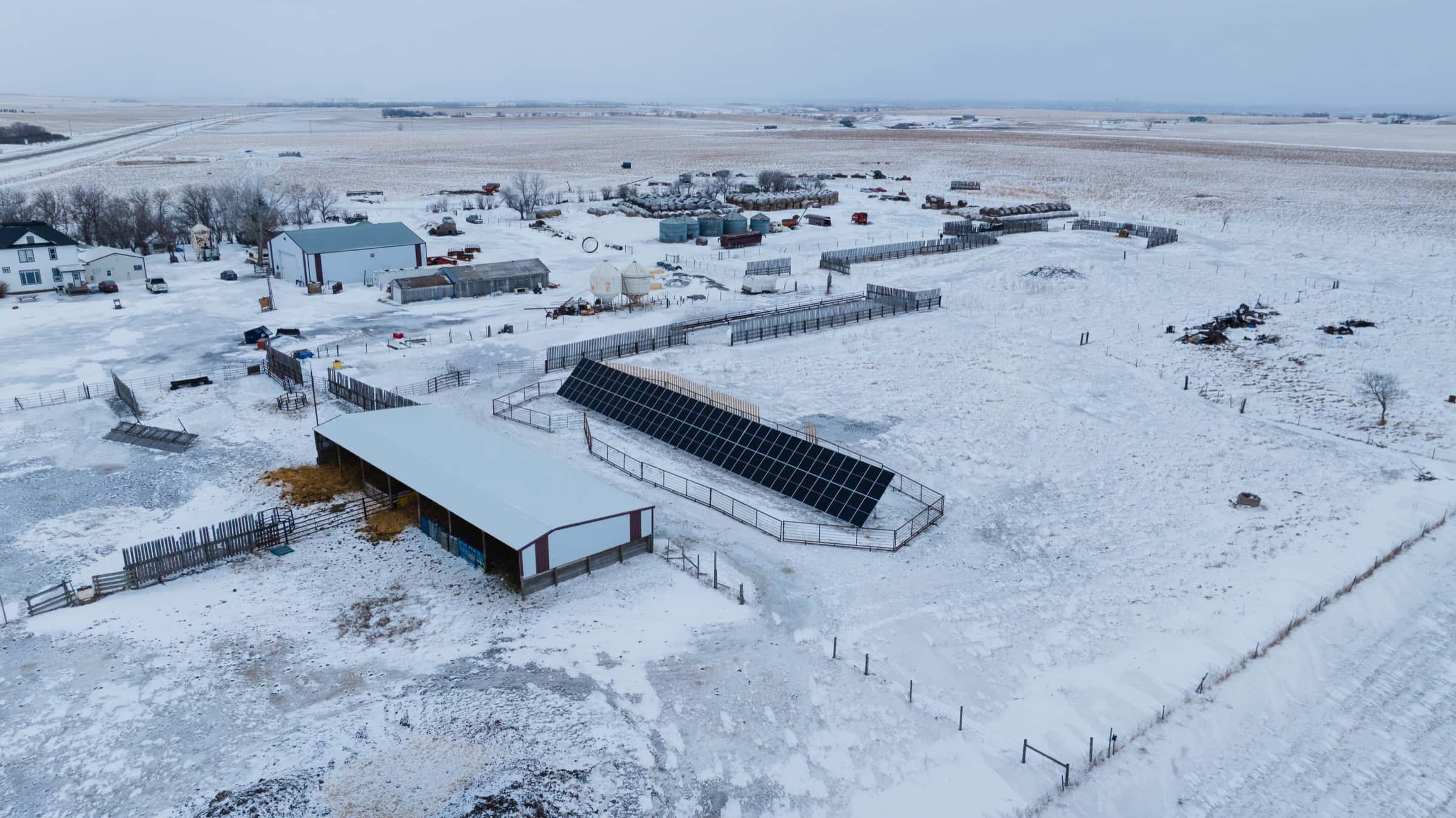 Aerial view of the Mackenzie farmyard in winter, with the ground-mount solar array running alongside a livestock shelter