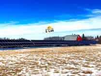The Tilson ground-mount solar array seen across a stubble field under a wide prairie sky