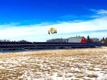 The Tilson ground-mount solar array seen across a stubble field under a wide prairie sky